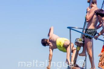 Un băiat adolescent sărind de pe prova unei barci