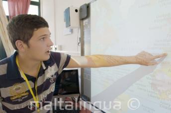 A student pointing to a map în clasă