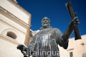 O statuie în Malta a unui om ținând un pergament