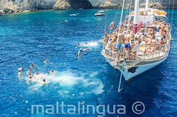 Language studenți jumping off a boat at Crystal Bay, Comino.