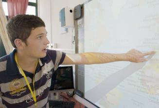 A student pointing to a map în clasă