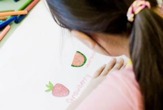 A young student drawing and writing in engleză