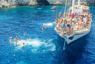 Language studenți jumping off a boat at Crystal Bay, Comino.